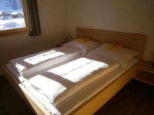a bed with two white sheets and a window at Haus Zitterklapfen in Au im Bregenzerwald
