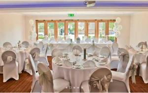 a banquet hall with white tables and white chairs at The Boleyn Hotel in Staines