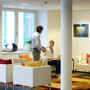 dos hombres en una oficina hablando con una mujer en SPES Hotel & Seminare, en Schlierbach