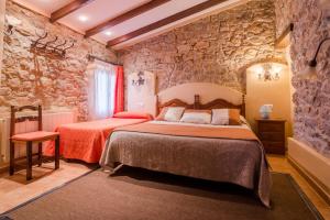 a bedroom with two beds and a stone wall at Casa Banys L'Avellà in L’Avellà