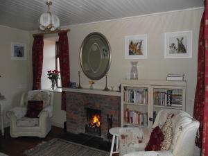 a living room with a fireplace and a mirror at James Tymon Self-Catering Cottage in Gorteen