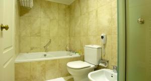 a bathroom with a toilet and a tub and a sink at Austral Plaza Hotel in Comodoro Rivadavia +38 photos