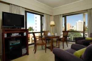 a living room with a television and a table with chairs at Austral Plaza Hotel in Comodoro Rivadavia