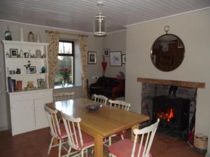 een keuken en eetkamer met een tafel en een open haard bij James Tymon Self-Catering Cottage in Gorteen