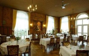 un comedor con mesas y sillas blancas y ventanas en Hôtel Des Vosges, en Lutzelbourg