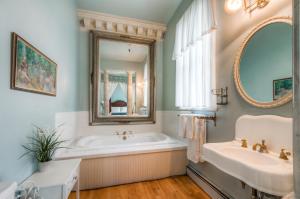 a bathroom with a tub and a sink and a mirror at Lumber Baron Inn and Gardens in Denver
