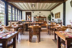 a restaurant with wooden tables and chairs and windows at Pousada Chão de Minas in Cachoeira do Campo