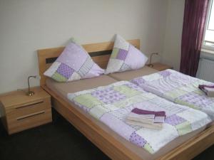 ヴィリンゲンにあるStrycker Ferienappartementのベッド(紫と白のキルト、枕付)