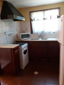 a kitchen with a stove and a sink and a microwave at Villa Cristina in Punta del Este