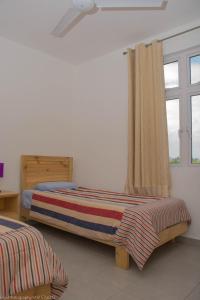 een slaapkamer met 2 bedden en een raam bij Villa Alexis - Location de vacances à Trou aux Biches in Trou aux Biches