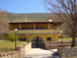una grande casa gialla con una recinzione di fronte di Agriturismo Centuria a San Pio delle Camere
