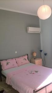 ナフプリオにあるAnastasia Apartmentのベッドルーム1室(ピンクのシーツとランプ付きのベッド1台付)