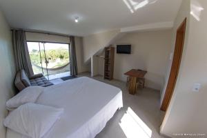 um quarto com uma grande cama branca e uma janela em Recanto Sol&Mar na Praia do Rosa