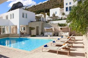 a villa with a swimming pool and lounge chairs at Skyros Ammos Hotel in Skiros
