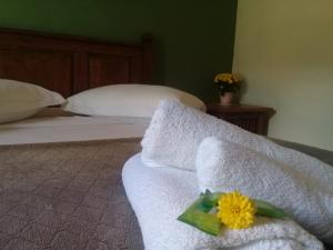 Una cama con toallas blancas y una flor amarilla. en Pousada Nascer do Sol, en Tiradentes