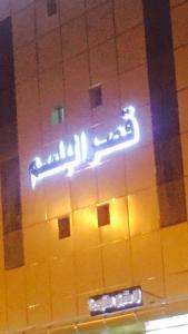 ein Neonschild, das an der Seite eines Gebäudes hängt in der Unterkunft Qsr Al Balsem Aparthotel in Unaizah