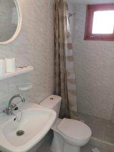 a white bathroom with a toilet and a sink at Studio in Poros in Poros