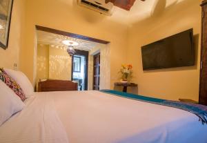 a bedroom with a large white bed with a flat screen tv at Casa El Carretero Hotel Boutique in Cartagena de Indias