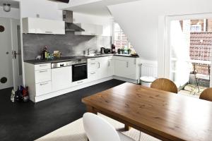 a kitchen with white cabinets and a wooden table at Altstadt-Domizil 6 in Leer