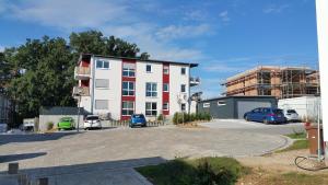 a large white building with cars parked in a parking lot at FeAp Brombachsee - Sonnentag Ost in Röttenbach