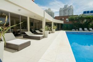 a patio with a pool and chairs and a building at Apartamento Torre Cristal in Punta del Este