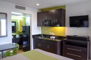 a kitchen with dark brown cabinets and a black refrigerator at Studio 6-Buttonwillow, CA in Buttonwillow