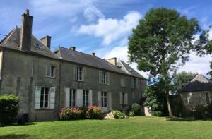 une grande maison en pierre avec une grande cour dans l'établissement Les Escuries, à Commes