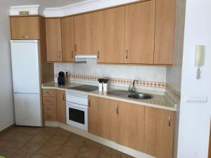 a kitchen with wooden cabinets and a sink and a refrigerator at alquilaencanarias El Medano Sotavento, Great Terrace and beach in El Médano