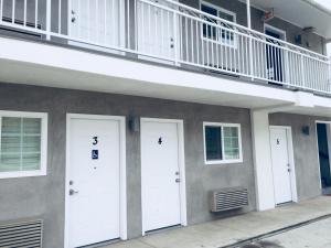 a building with three white doors and a balcony at Value Inn in Sylmar