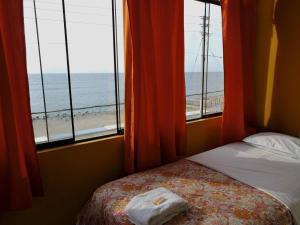 a bedroom with a bed and a view of the beach at Hostal Miramar in Pisco