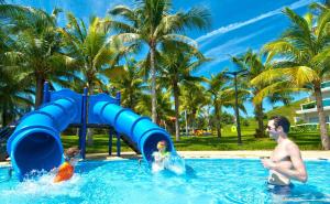a man and two children playing in the water at a pool at Sea Links Beach Resort & Golf in Mui Ne
