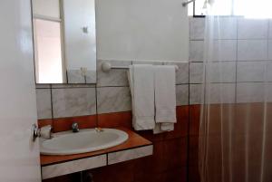 y baño con lavabo, espejo y toallas. en Hostal Miramar, en Pisco