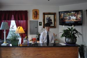 a man in a tie sitting at a desk at Golden Lion Motel in Raymond