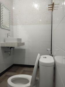 a white bathroom with a toilet and a sink at Tirta Yoga Inn in Padangbai