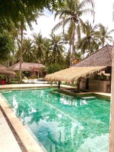 una piscina con sombrilla y palmeras en Trawangan Oasis, en Gili Trawangan