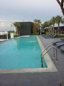 a swimming pool with blue water and lounge chairs at The Chezz by Patsamon in Pattaya