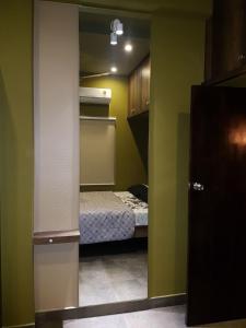 a small bedroom with a bed in a room with green walls at Belen - Service Apartment in Mangalore