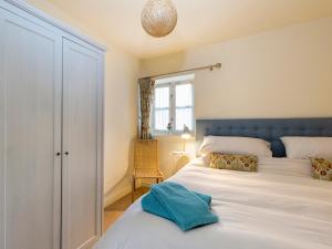 a bedroom with a bed with a blue headboard and a window at The Leat at Wynyard Mill in Malmesbury