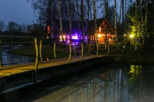 a house with lights in front of a river at night at Guest House Vējaines in Vecslavēkas