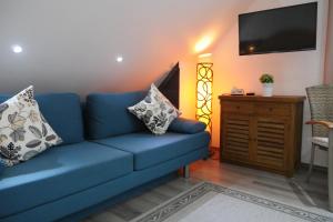 un sofá azul en la sala de estar con TV de pantalla plana en Hotel Refrather Hof, en Bergisch Gladbach