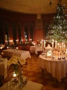 une salle à manger avec des tables, des bougies et un arbre de Noël dans l'établissement Al Borducan Romantic Hotel - Adults Only, à Varèse