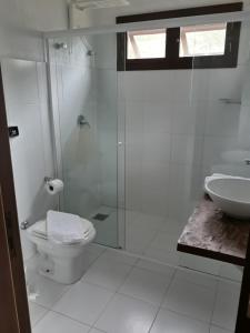 een badkamer met een douche, een toilet en een wastafel bij Pousada Águas de Ibiraquera Suíte Luz in Imbituba