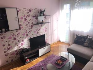 Apartman Ivana في نوفي ساد: غرفة معيشة مع زهور وردية على الحائط