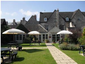 a large building with tables and umbrellas in the grass at Corinium Hotel & Restaurant in Cirencester