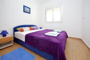 sypialnia z łóżkiem z fioletowym kocem i oknem w obiekcie Apartments Kristina w Bibinje
