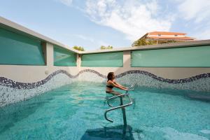 a woman in a swimming pool next to a building at Thomais Boutique Hotel in Nikiana