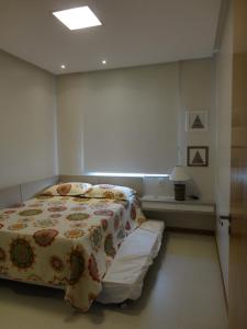 a bedroom with a bed with a flowered blanket at Guarajuba Verano in Guarajuba