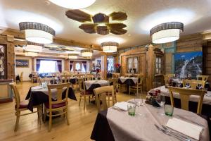 un ristorante con tavoli, sedie e soffitto di Hotel Maso del Brenta a Caderzone