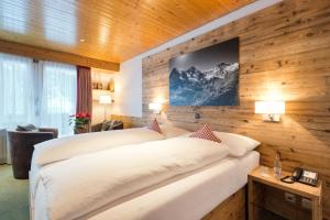 sypialnia z dużym łóżkiem w drewnianej ścianie w obiekcie Hotel Bernerhof Grindelwald w mieście Grindelwald