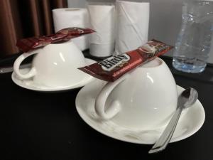 two white cups and spoons on a black table at R2 Apartment Service in Nakhon Ratchasima